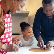 Little girl making Christmas gingerbread cookies with a grandparents