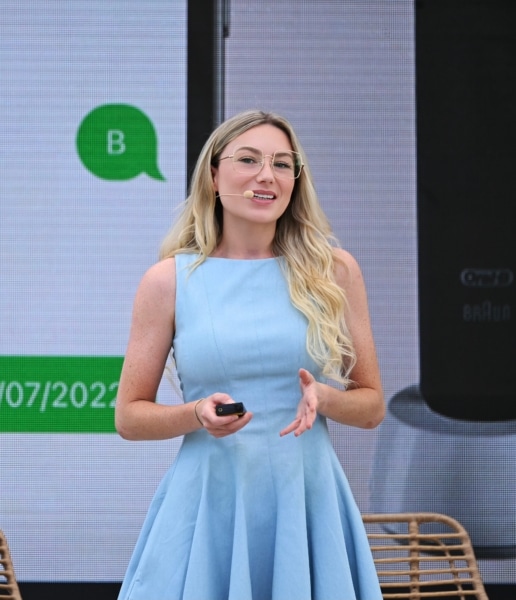 Photo of World Ostomy Day Champion Keely Cat-Wells a white woman with blond hair and a blue dress speaking at a professional conference.