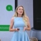 Photo of World Ostomy Day Champion Keely Cat-Wells a white woman with blond hair and a blue dress speaking at a professional conference.